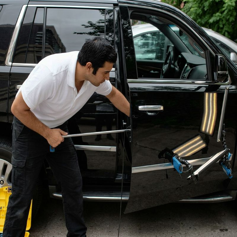 Pdr technician performing paintless dent repair on a Cadillac at New Beginnings Collision Center Pdr-technician-performing-paintless-dent-repair-on-a-Cadillac-at-New-Beginnings-Collision-Center